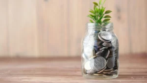 a glass jar full of coins with green shoots growing from the top