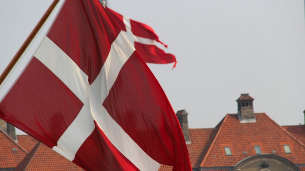 Danish flag flying in foreground infront of building