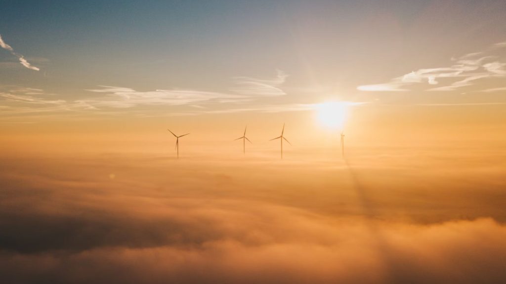 Sunrise over windmills visible above low cloud
